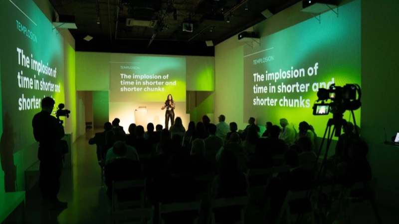 Presentation in the Immersive Studio with a speaker on stage and slides projected across the walls