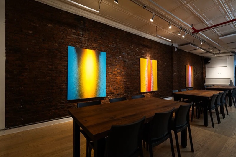 Long dinner tables under hanging art in the Tribeca dining loft