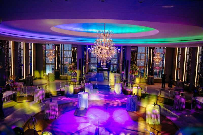 Dance floor under the domed ceiling lit in purple and blue with cocktail tables around it