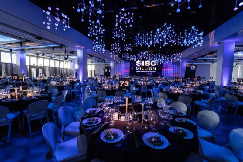 Gala dinner tables in blue light beneath the hanging orb light installation