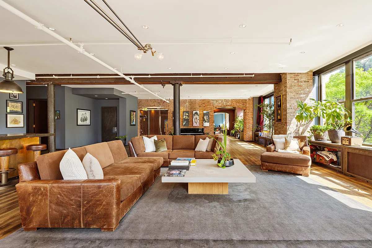 Great room with a leather sectional, exposed brick and tall windows