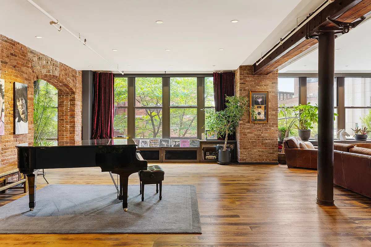 Living area with a grand piano, a cast-iron column and brick-framed windows
