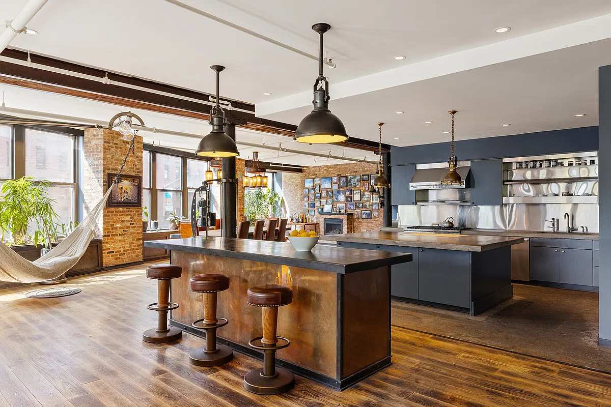Kitchen island with leather stools under brass pendants, fireplace and photo wall behind