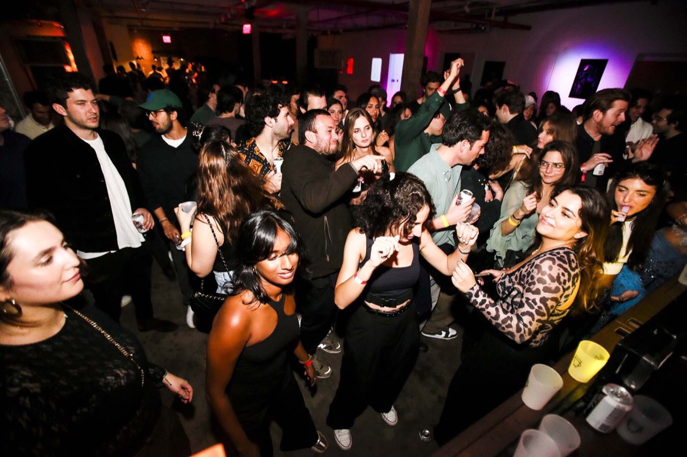 Crowded evening party on the loft dance floor near the bar