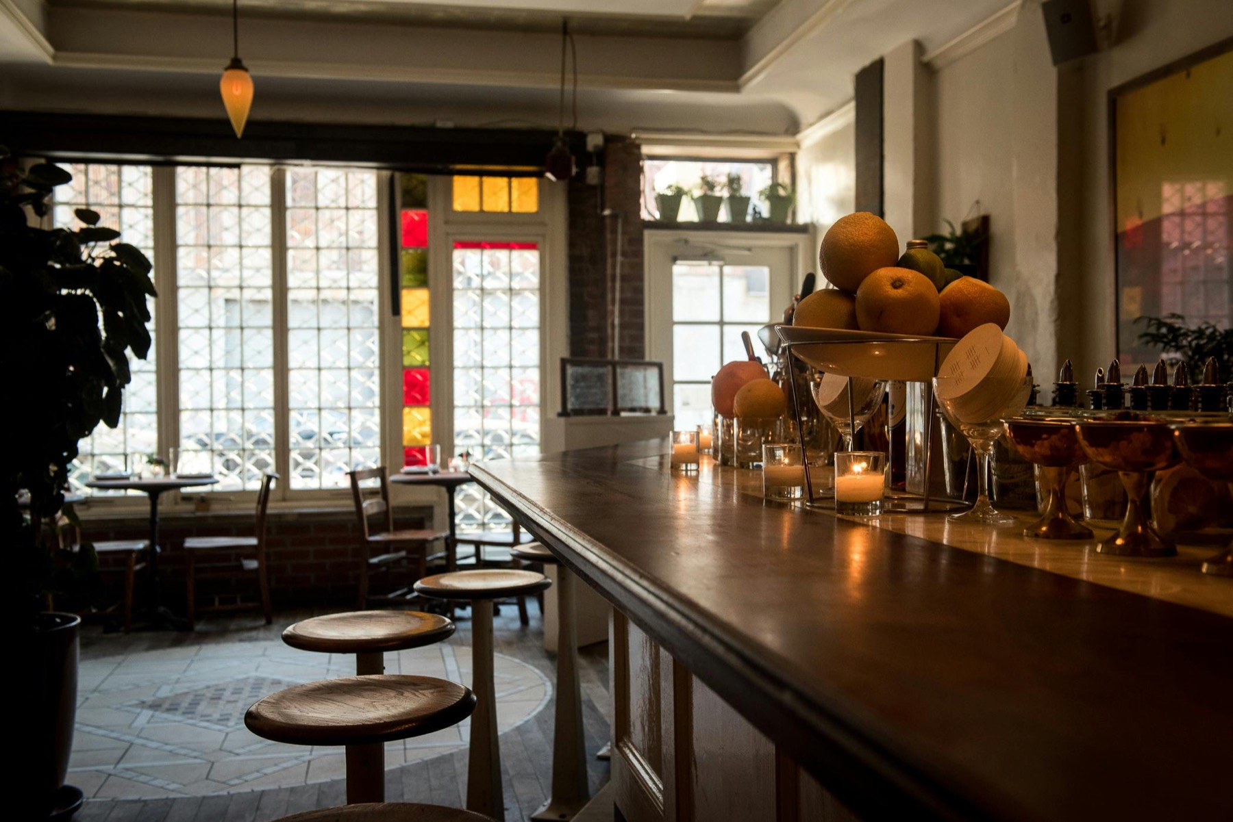 Front room with a long wood bar, stained glass windows and tall doors