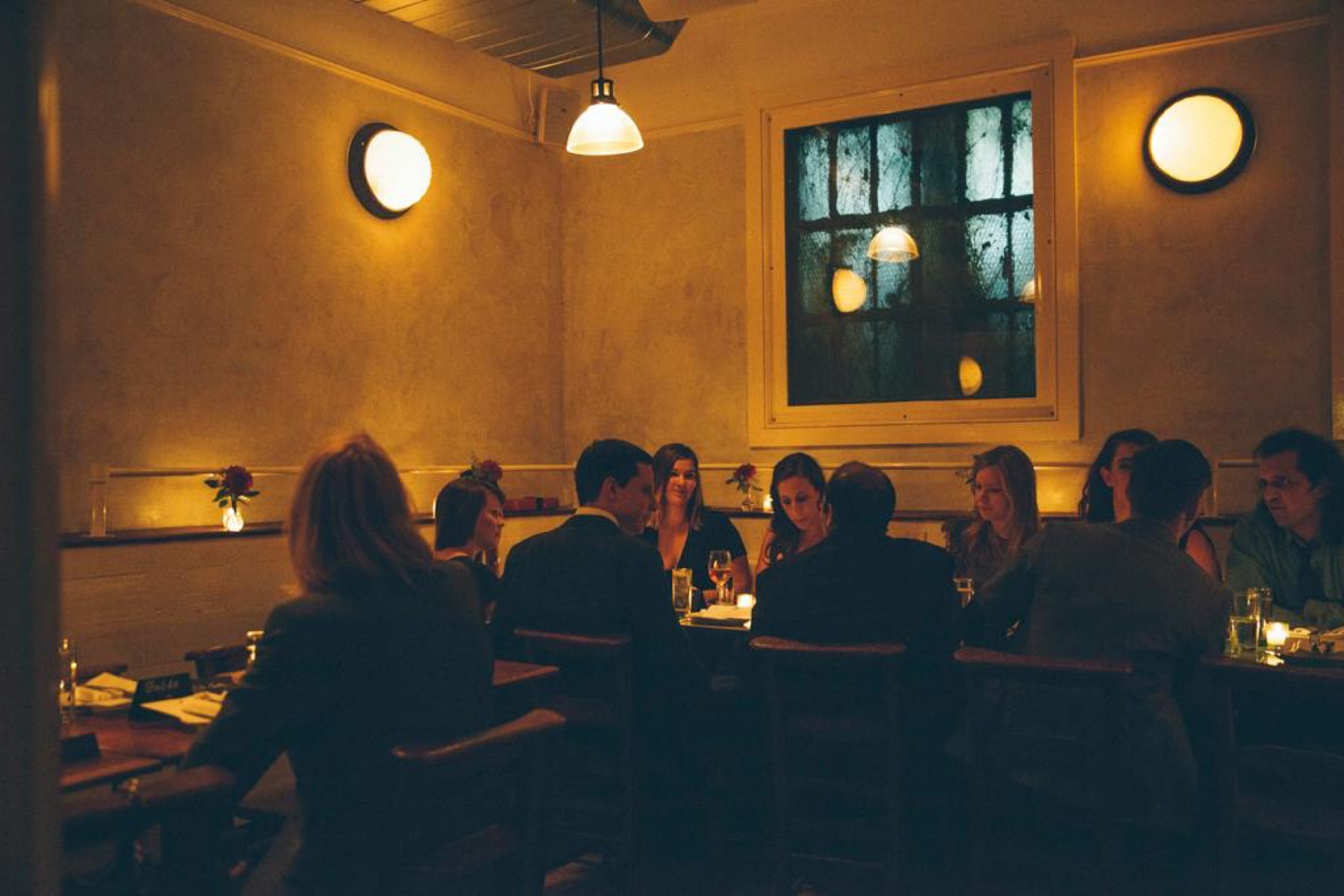 Candlelit group dinner in the back room under wall sconces
