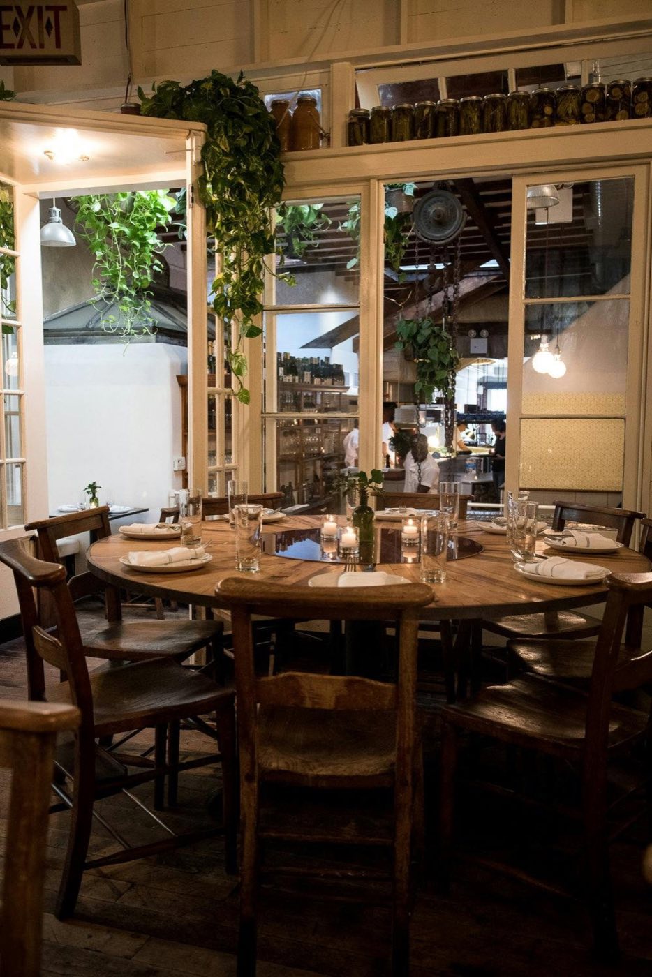 Raised back room with a round table, glass transoms and hanging plants
