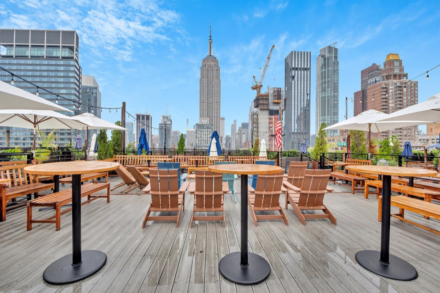 Rooftop deck with tables and umbrellas facing the Empire State Building