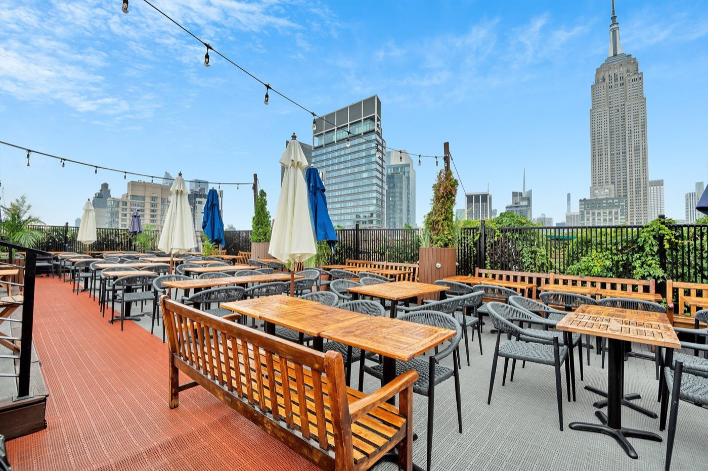 Rooftop seating area with string lights and midtown towers behind