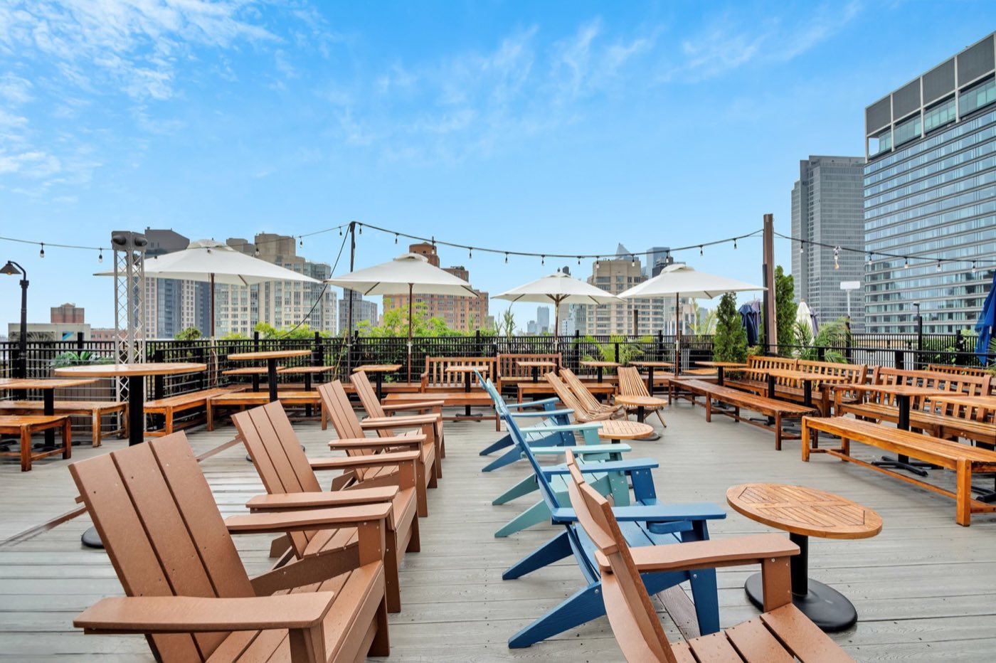 Rooftop lounge chairs and communal tables under a clear sky