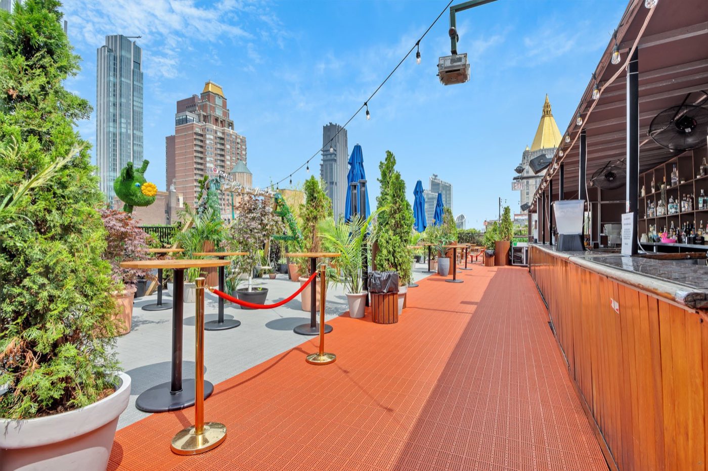 Planted rooftop walkway with a bar and skyline views