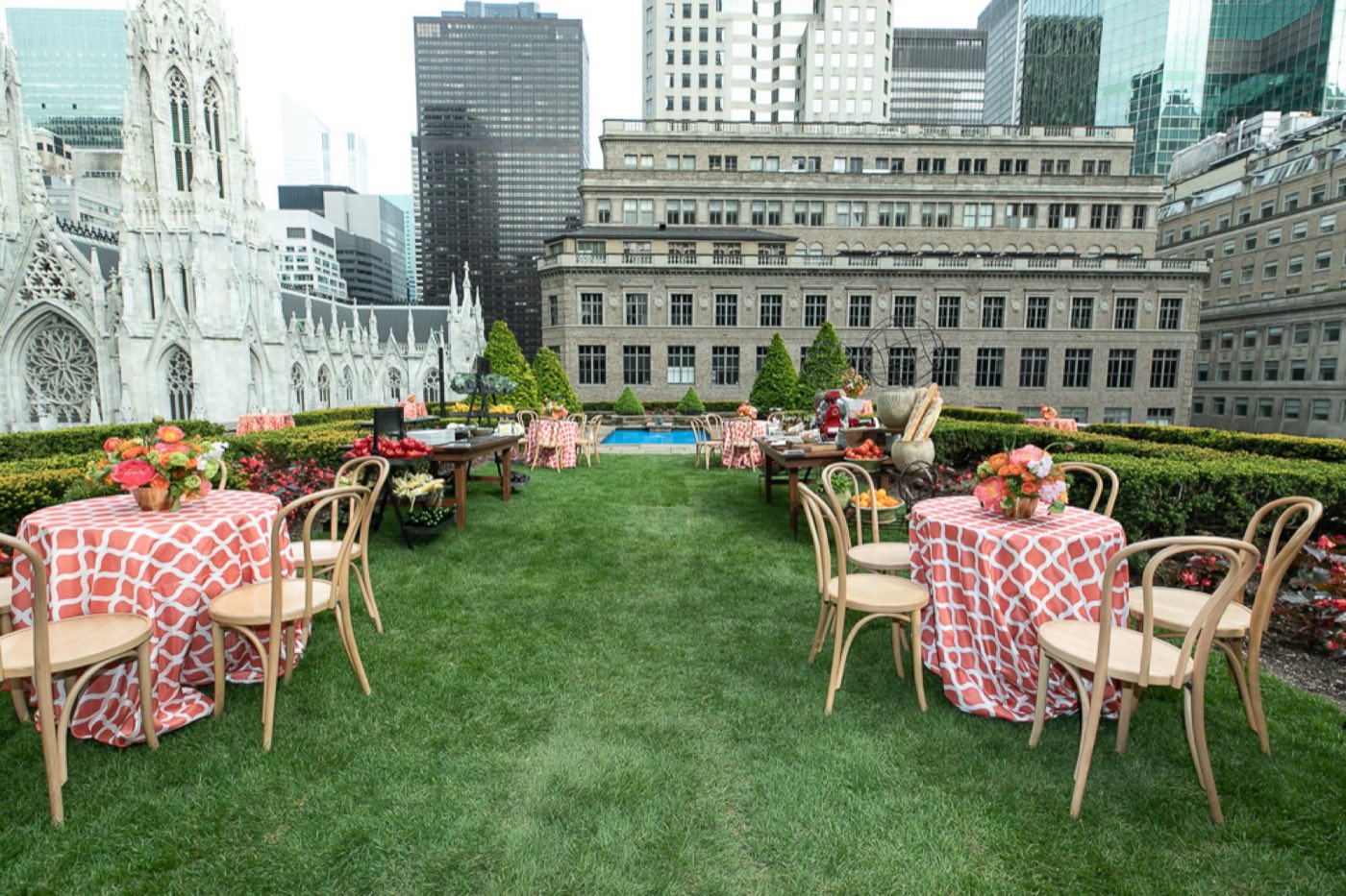 Rooftop lawn garden set with cocktail tables beside St. Patrick's Cathedral spires