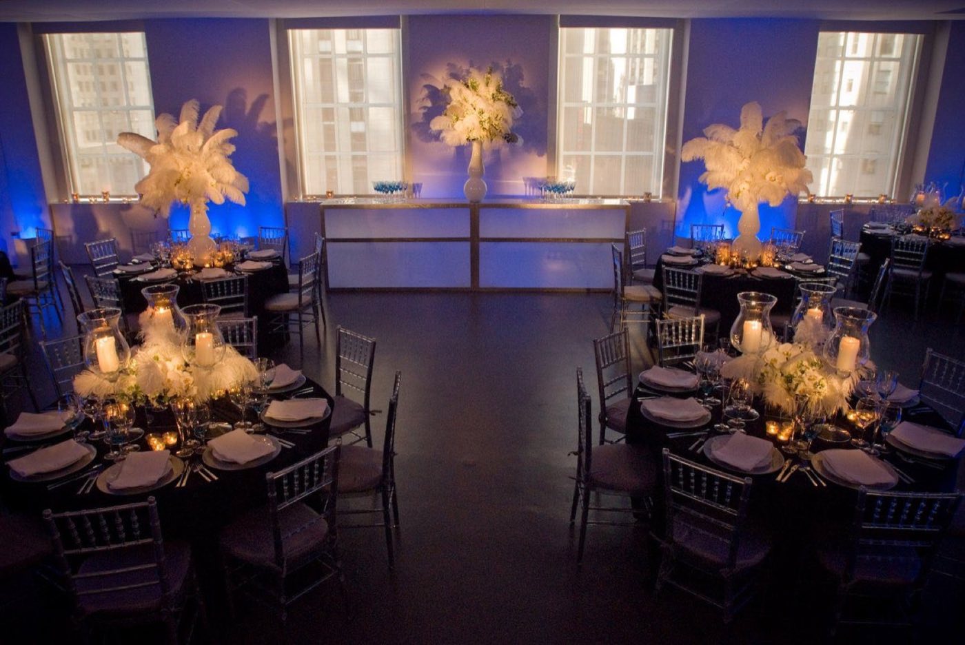 Indoor loft set for a seated dinner with round tables and blue uplighting
