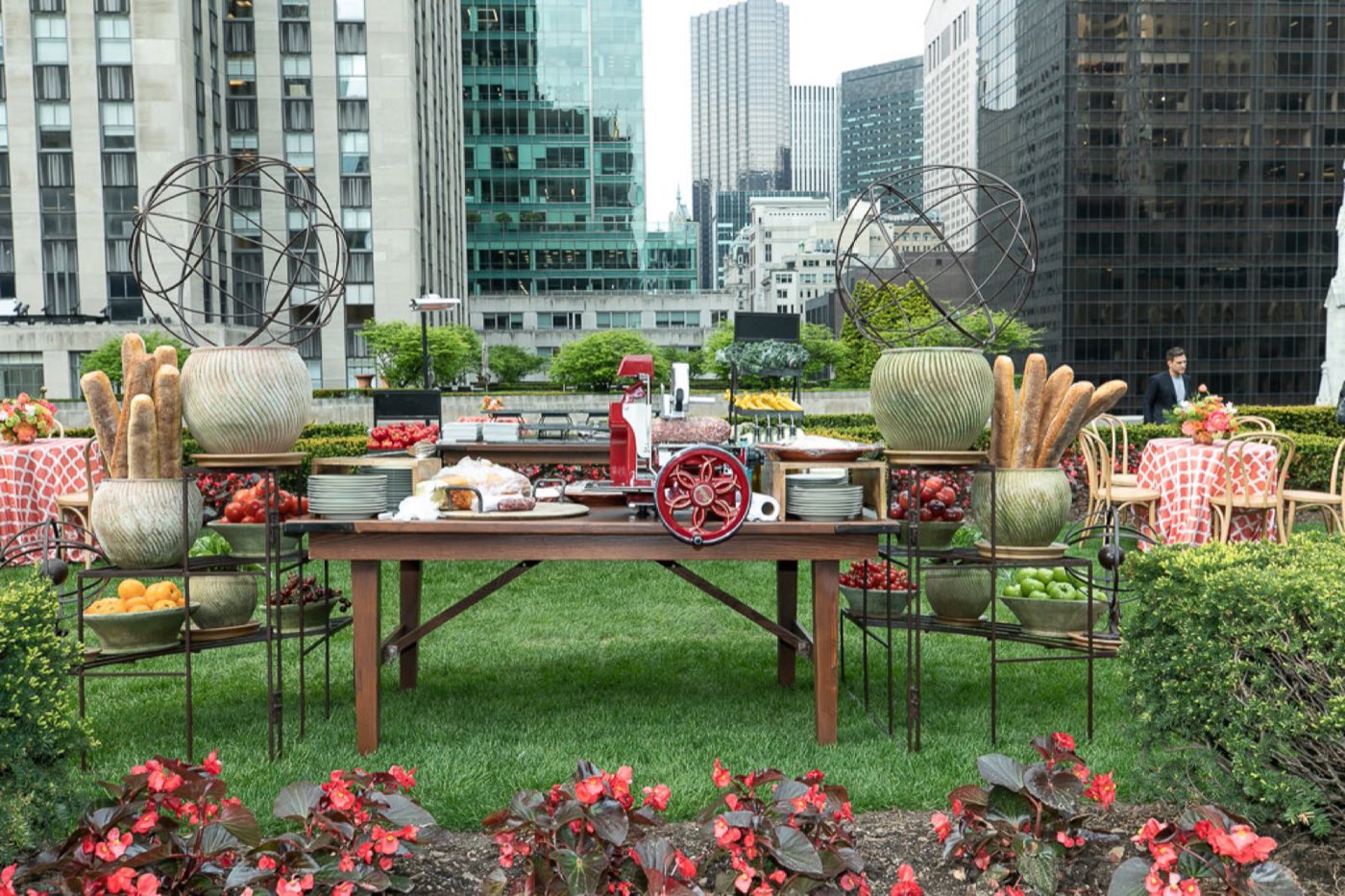 Rooftop garden lawn with a food station and flower beds among Midtown towers