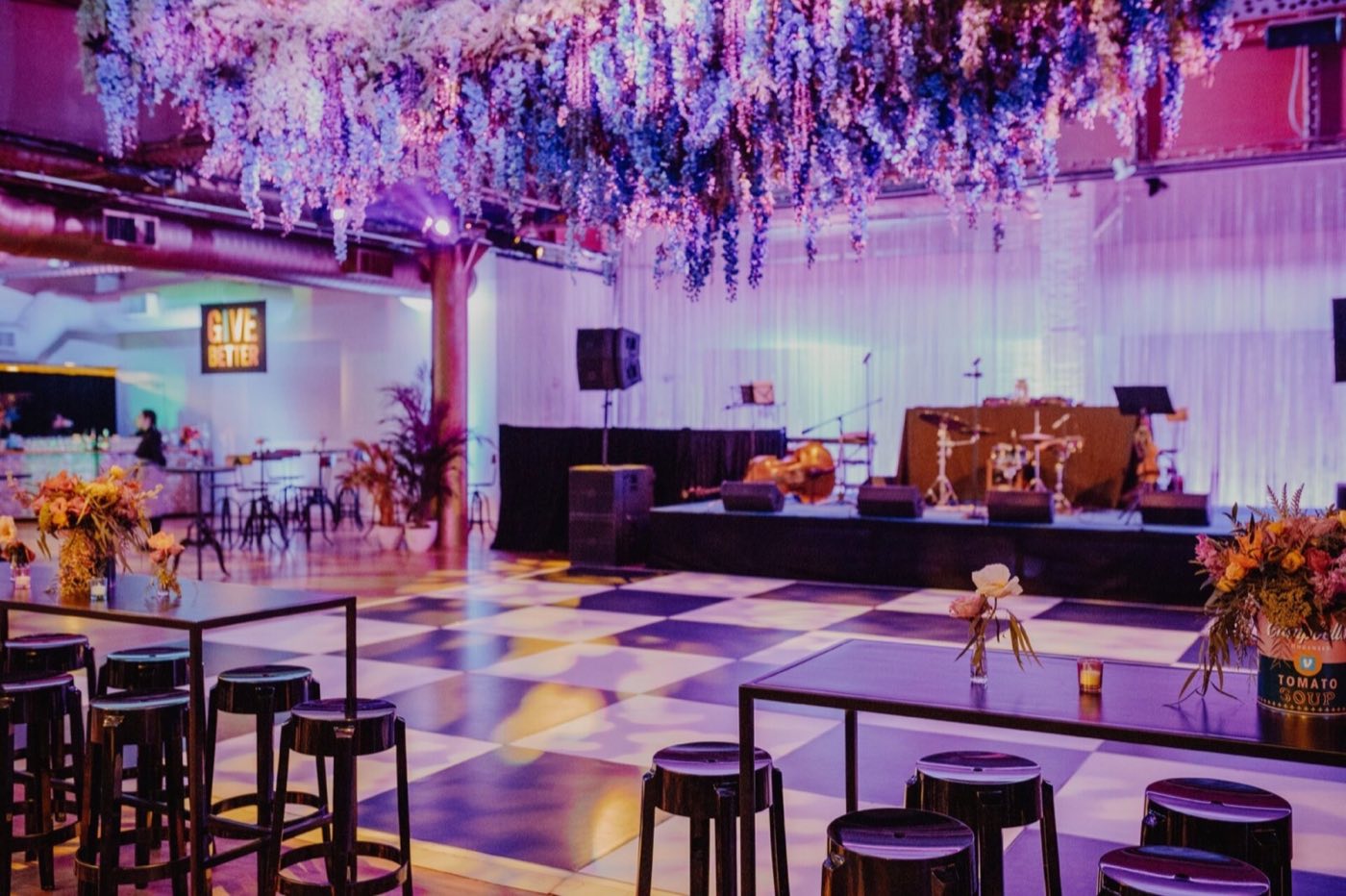 Event floor with checkered dance floor, stage and hanging floral ceiling