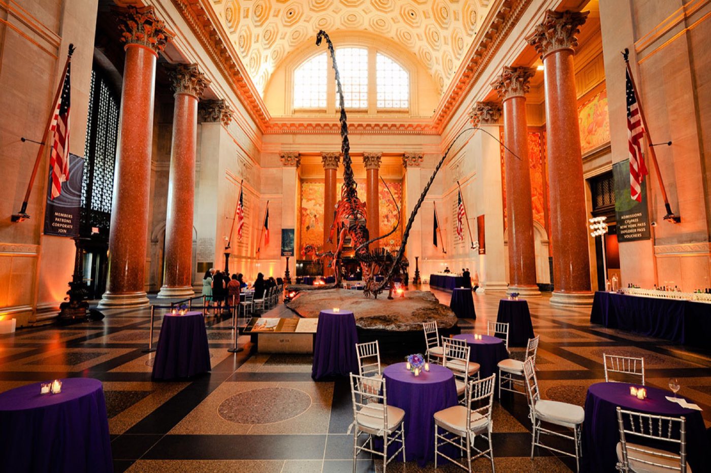 Theodore Roosevelt Rotunda set for a reception with cocktail tables beside the dinosaur skeletons