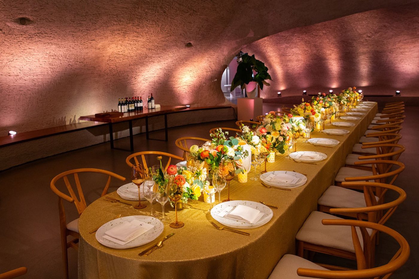 Long dinner table set inside the curved stone atrium of the Gilder Center