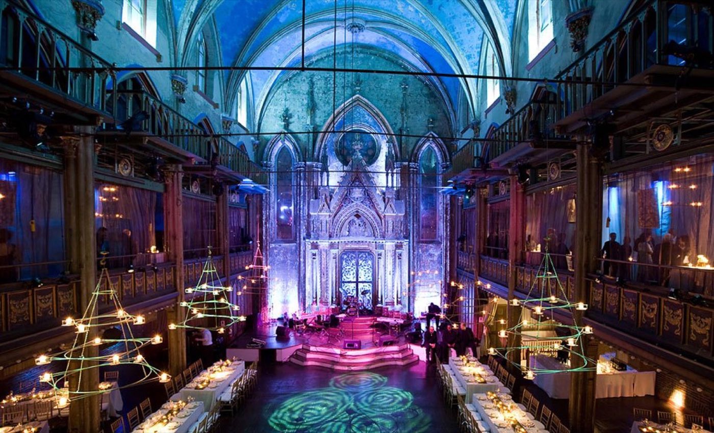 Gothic Revival sanctuary set for dinner with blue and purple uplighting