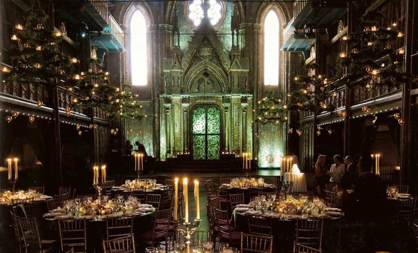 Candlelit round tables in the main hall facing the carved arch