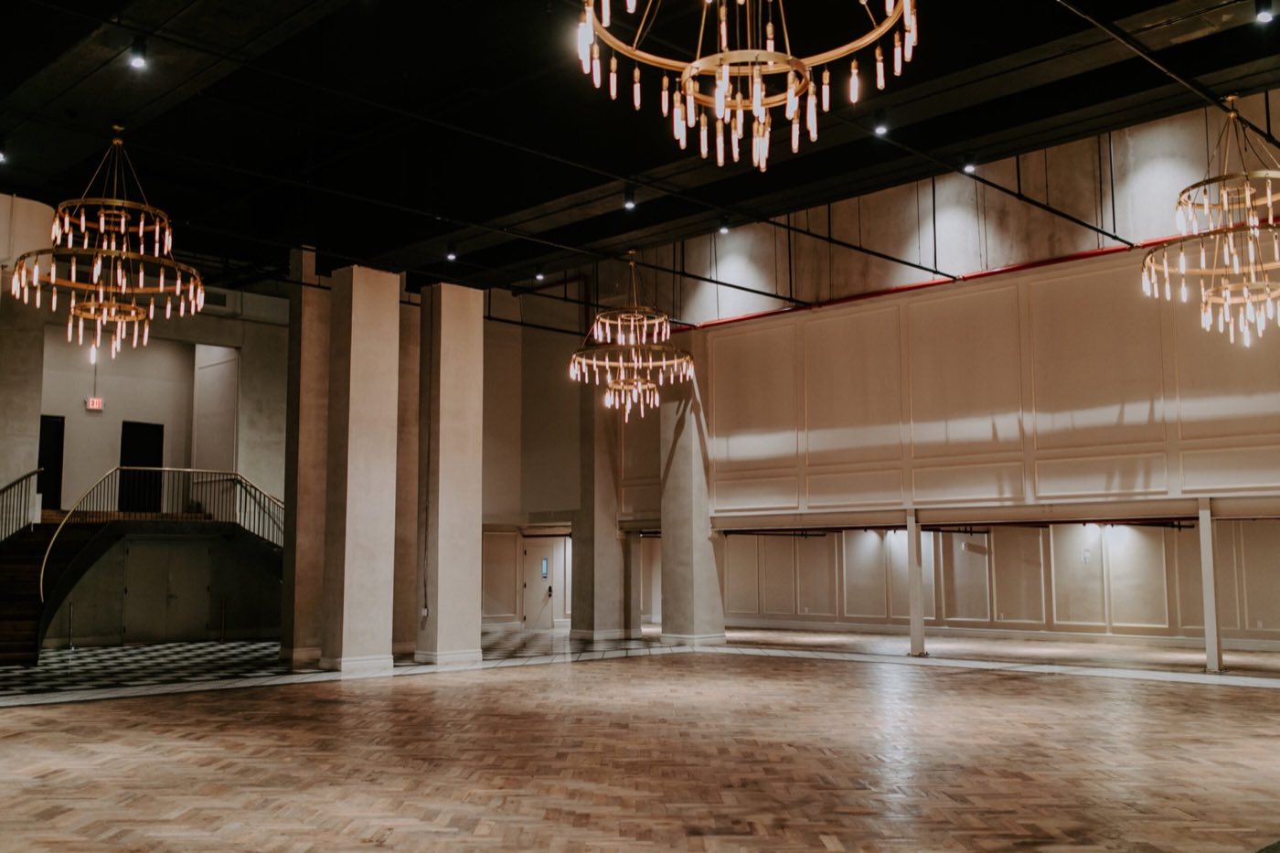 Empty hotel ballroom with parquet floor, chandeliers and a curved staircase