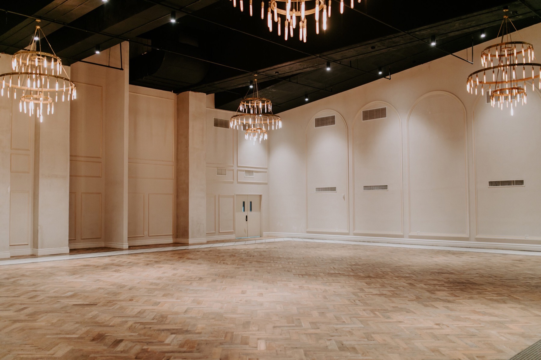 Open ballroom floor under tiered chandeliers with pale paneled walls