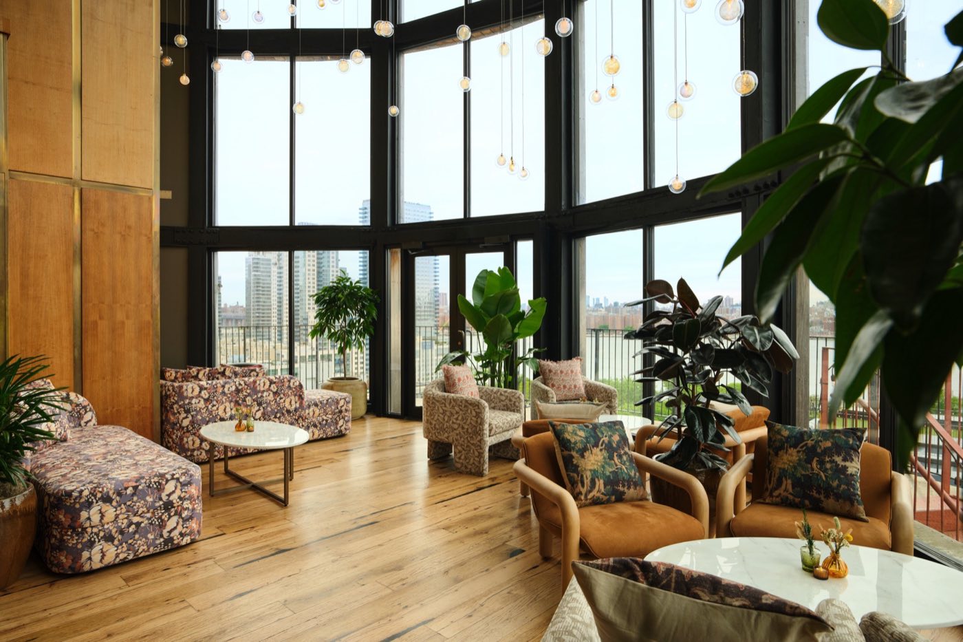 Glass-walled rooftop water tower lounge with plants and Manhattan views