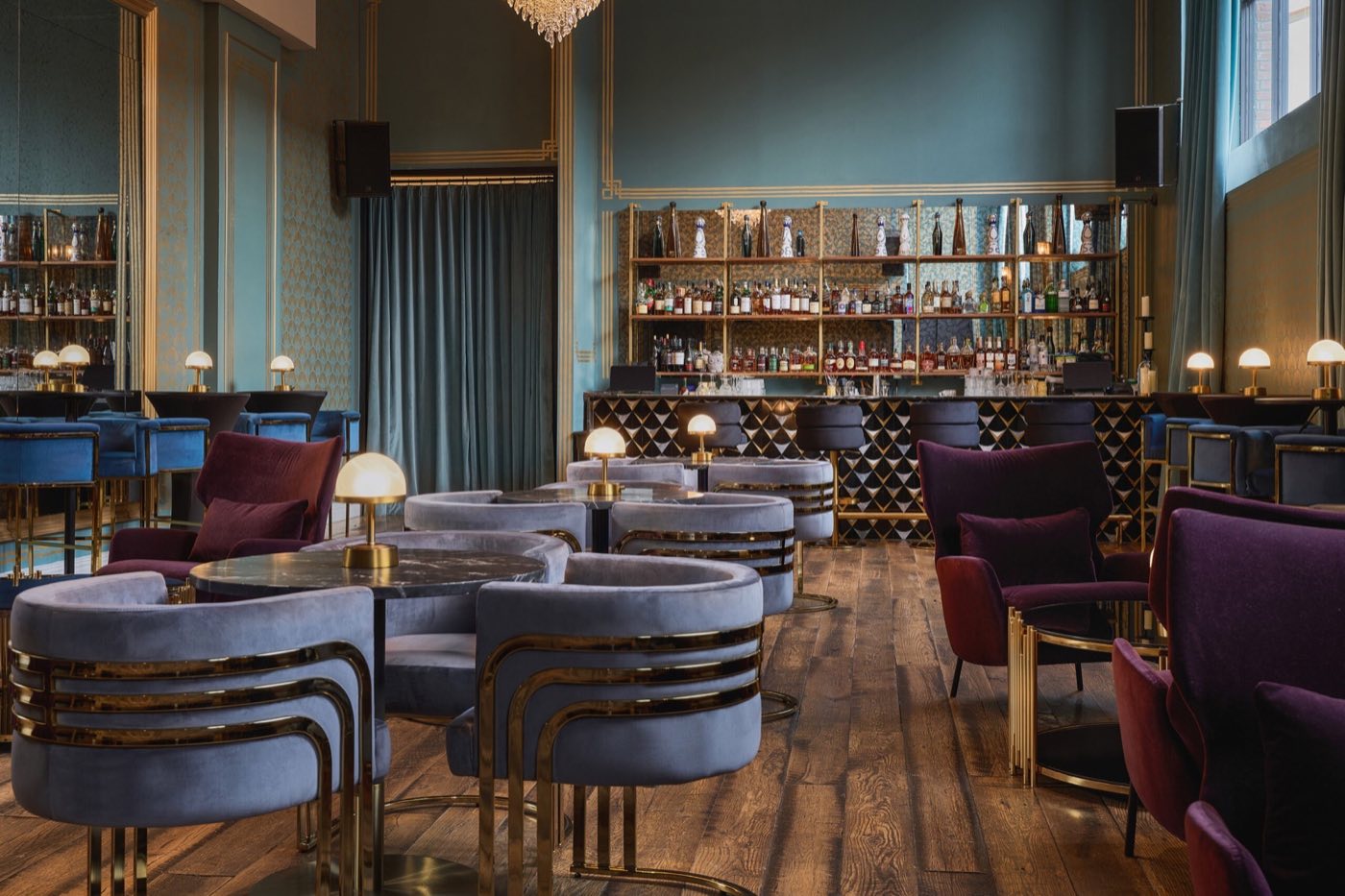 Mirror Bar with velvet chairs, marble bar and tall shelves of bottles