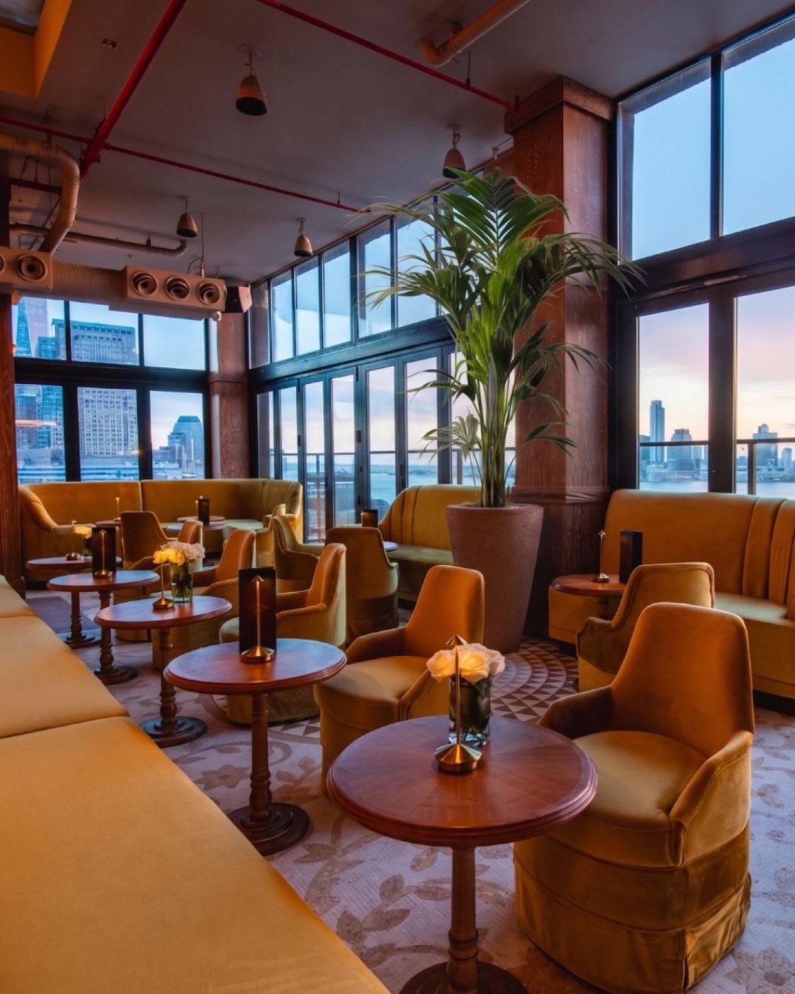 Bar Hugo lounge with velvet armchairs, round tables and floor-to-ceiling windows