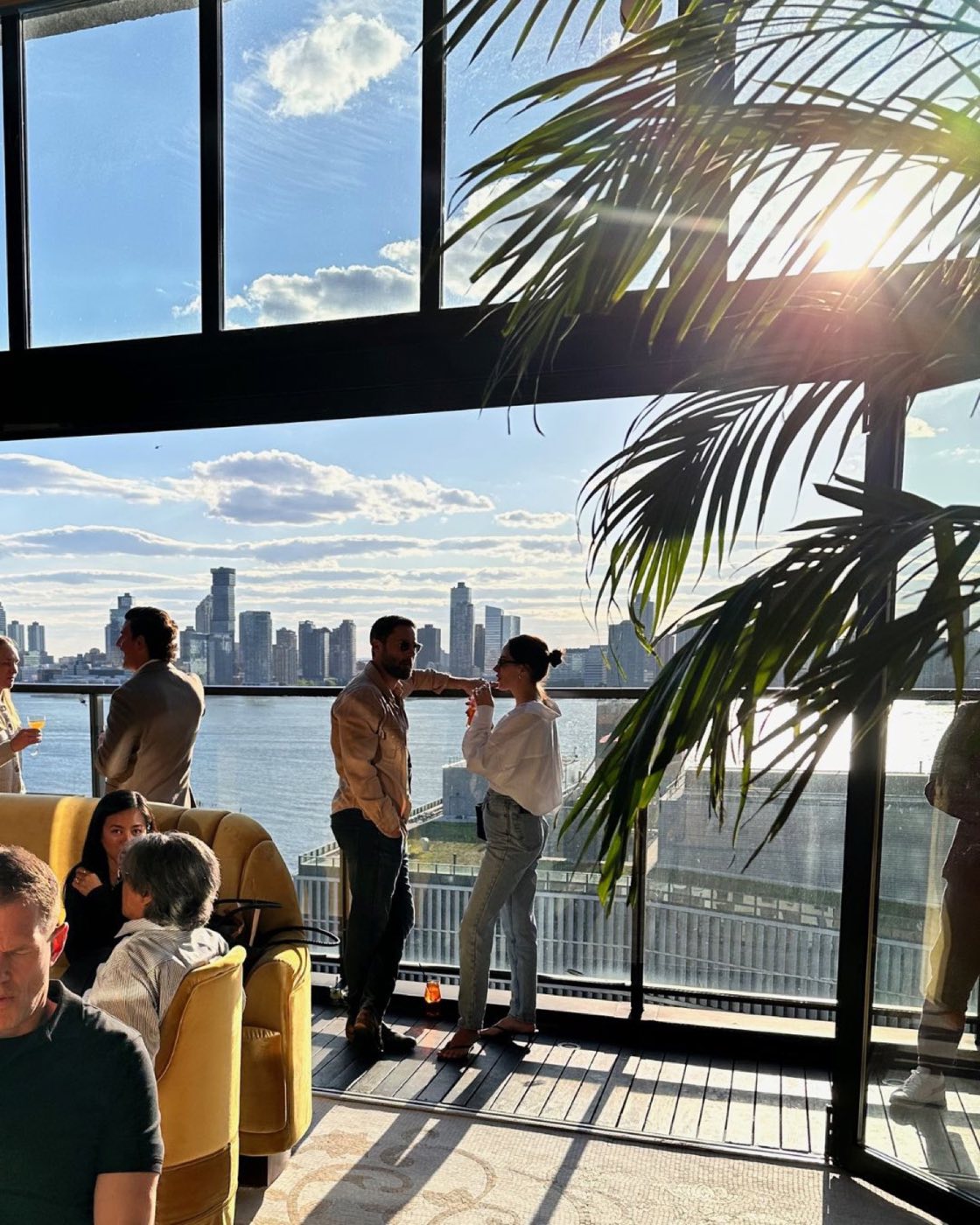 Guests at a reception by the glass wall overlooking the Hudson River