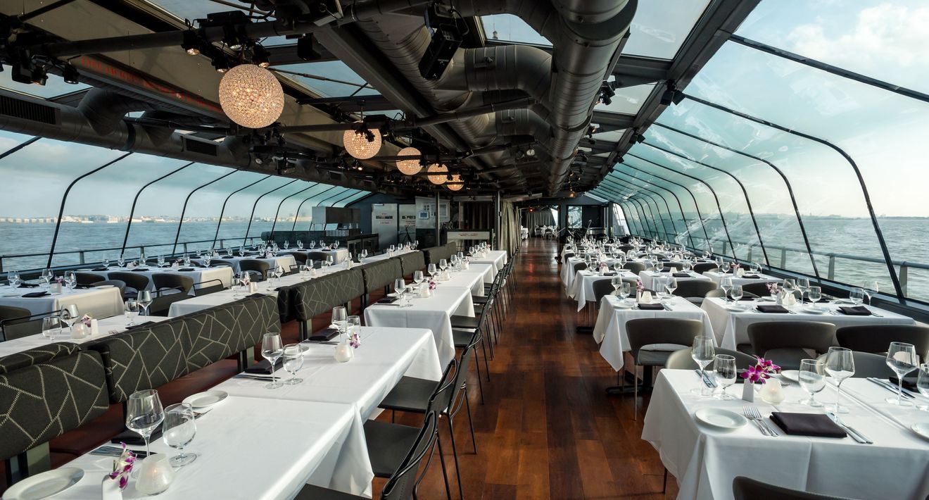 Rows of set tables and banquettes along the glass sides of the yacht