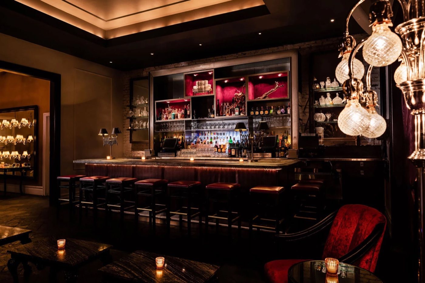 Candlelit bar with red velvet seating and crystal pendant lamps