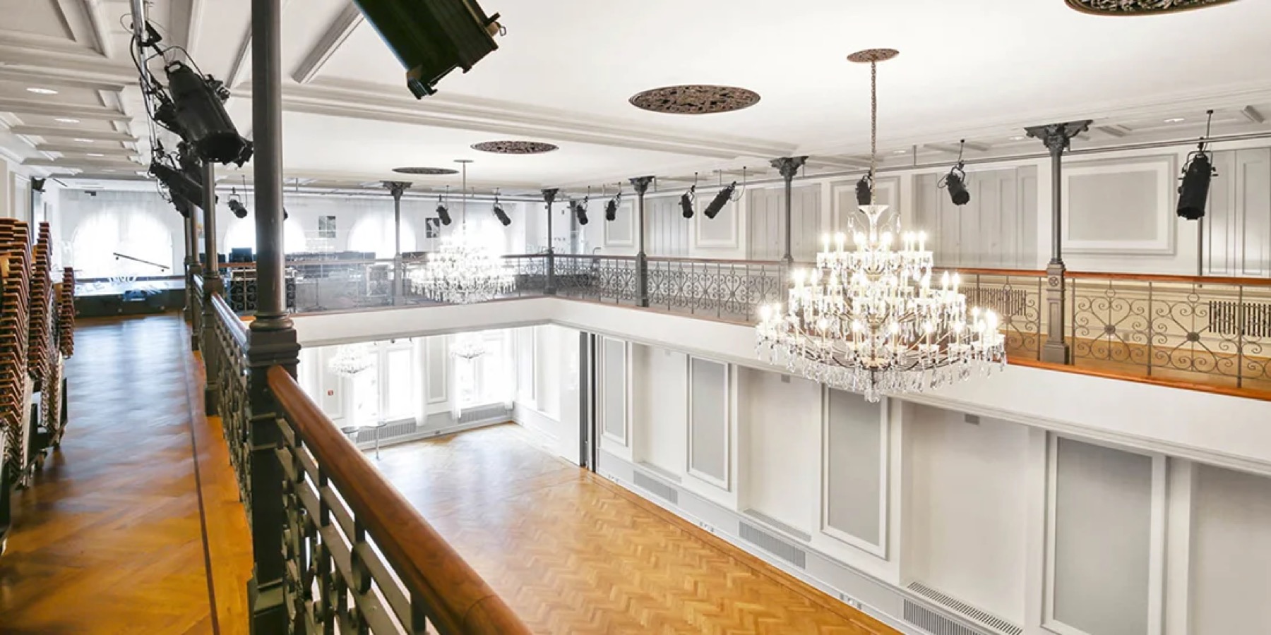 View from the balcony across the ballroom with crystal chandeliers and white paneled walls