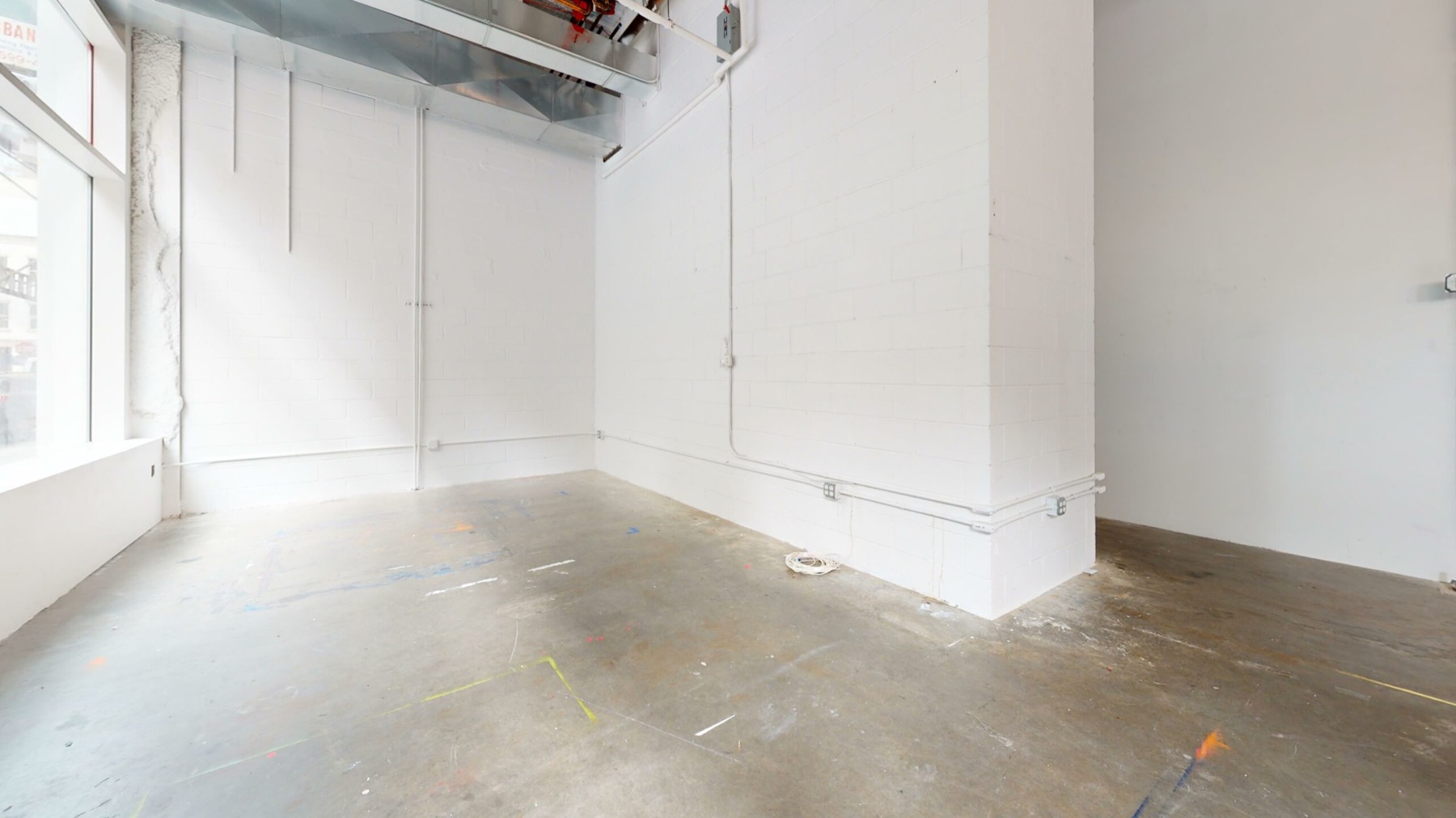 Bright empty corner of a white retail space with concrete floor and street window