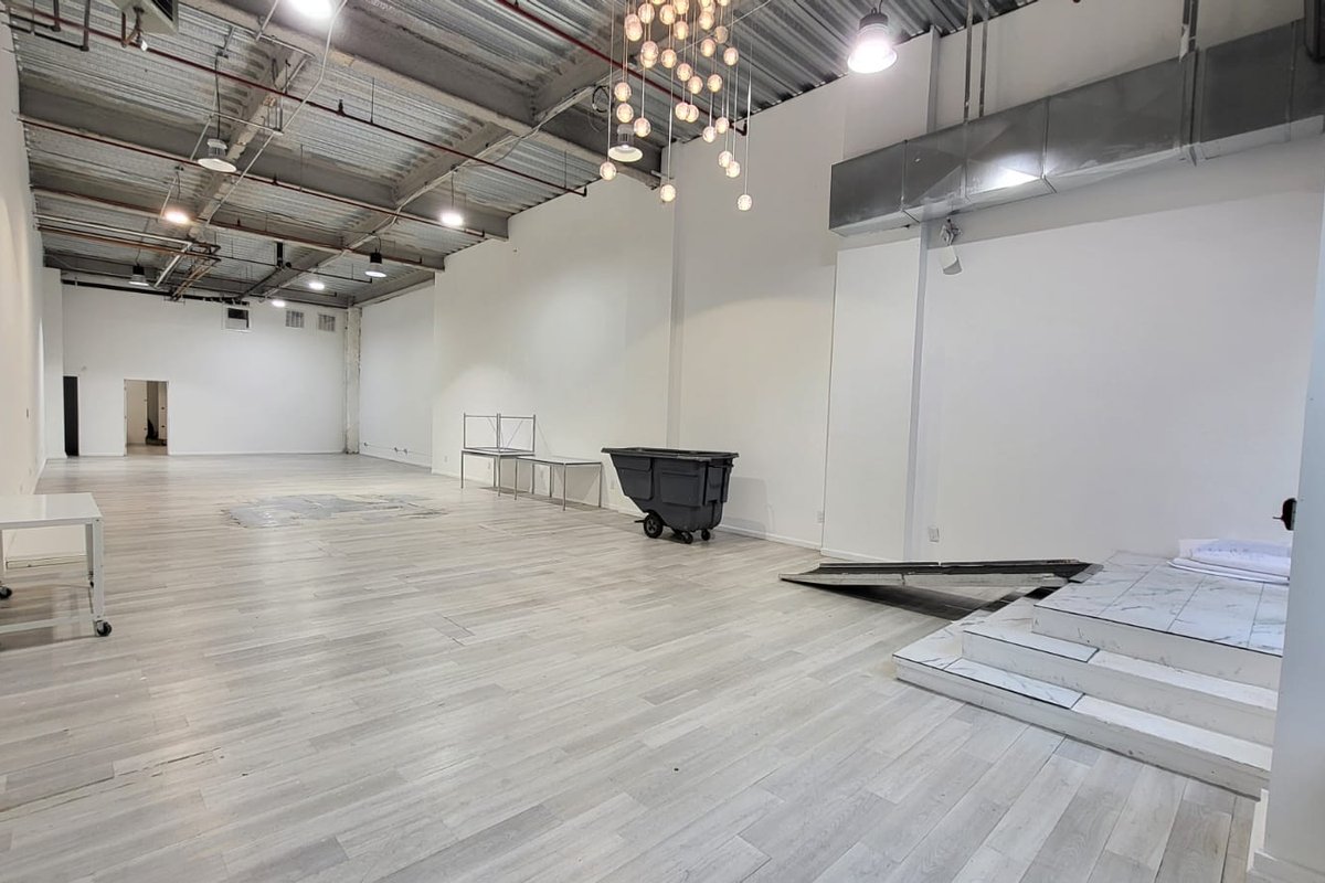 Deep whitebox retail floor with light wood flooring, high ceilings and a bulb chandelier