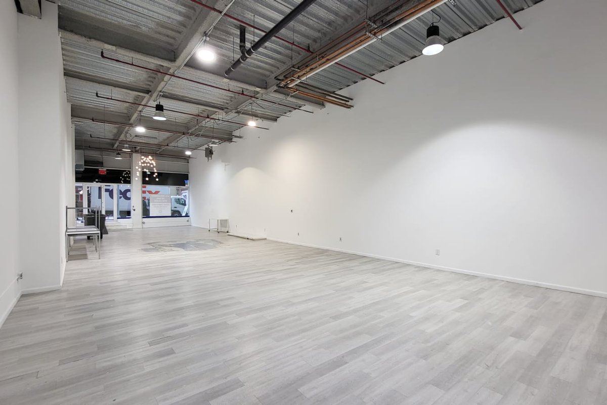 Long empty white retail space looking toward glass storefront windows on the street