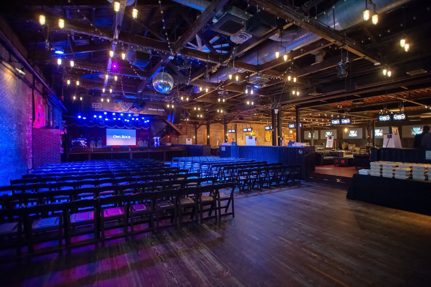 Main room set with rows of chairs facing a stage screen for a corporate program