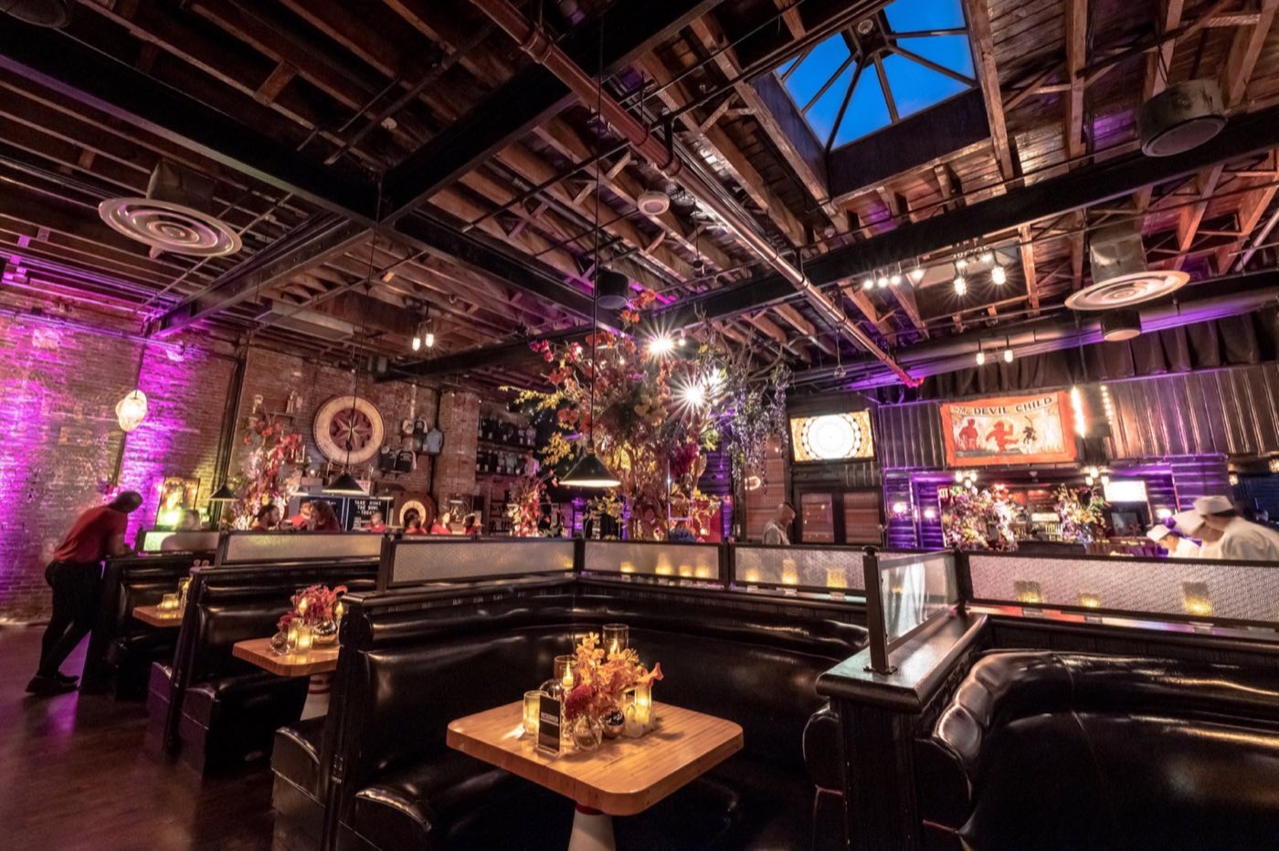 Restaurant booths with floral centerpieces under a skylight