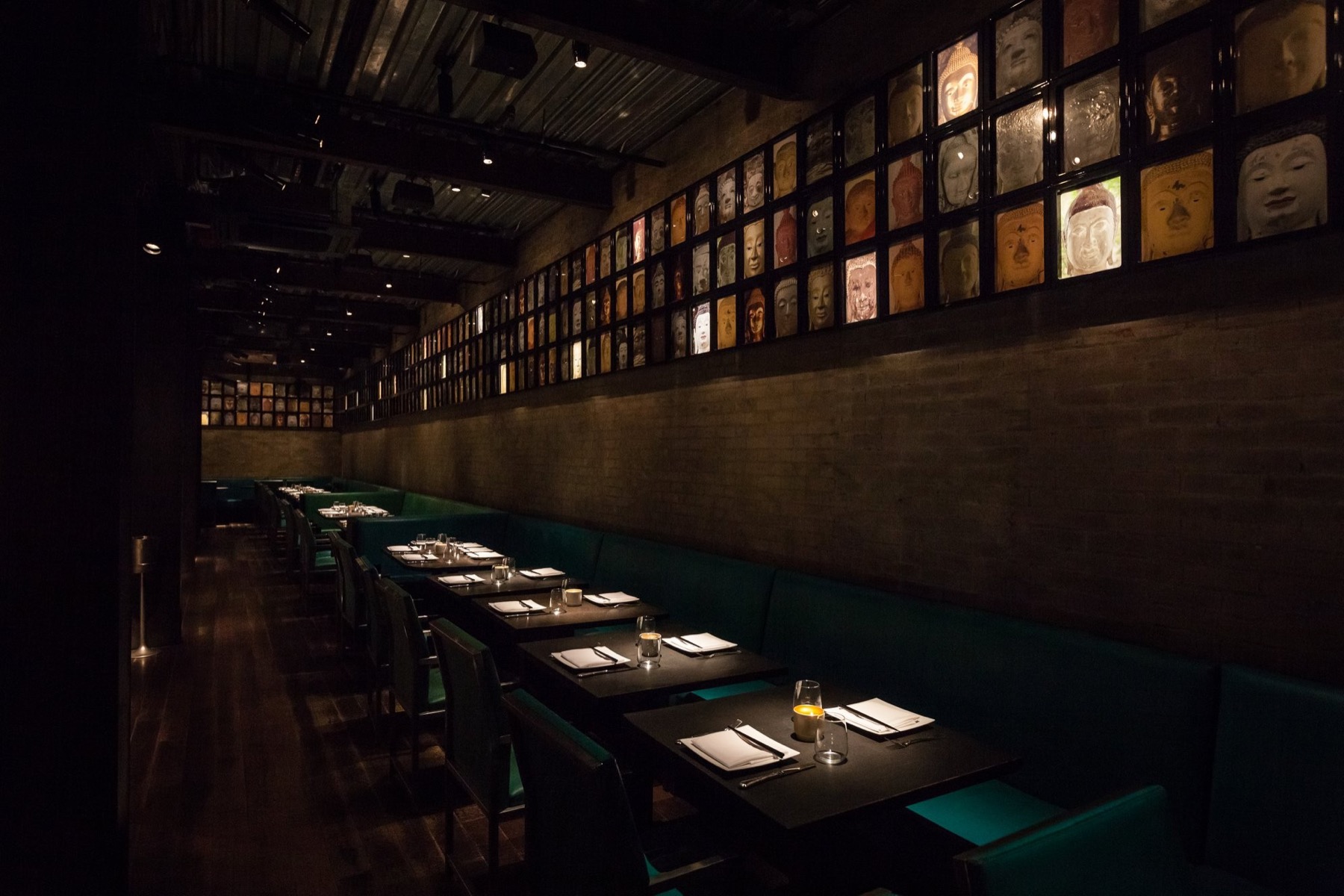 Long dark dining room with framed art along the wall and set tables
