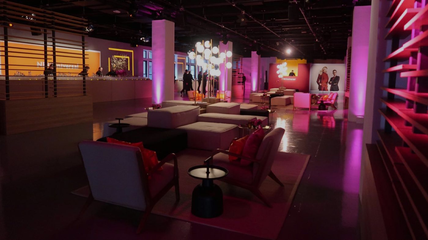Lounge setup with sofas, bar and pink uplit columns
