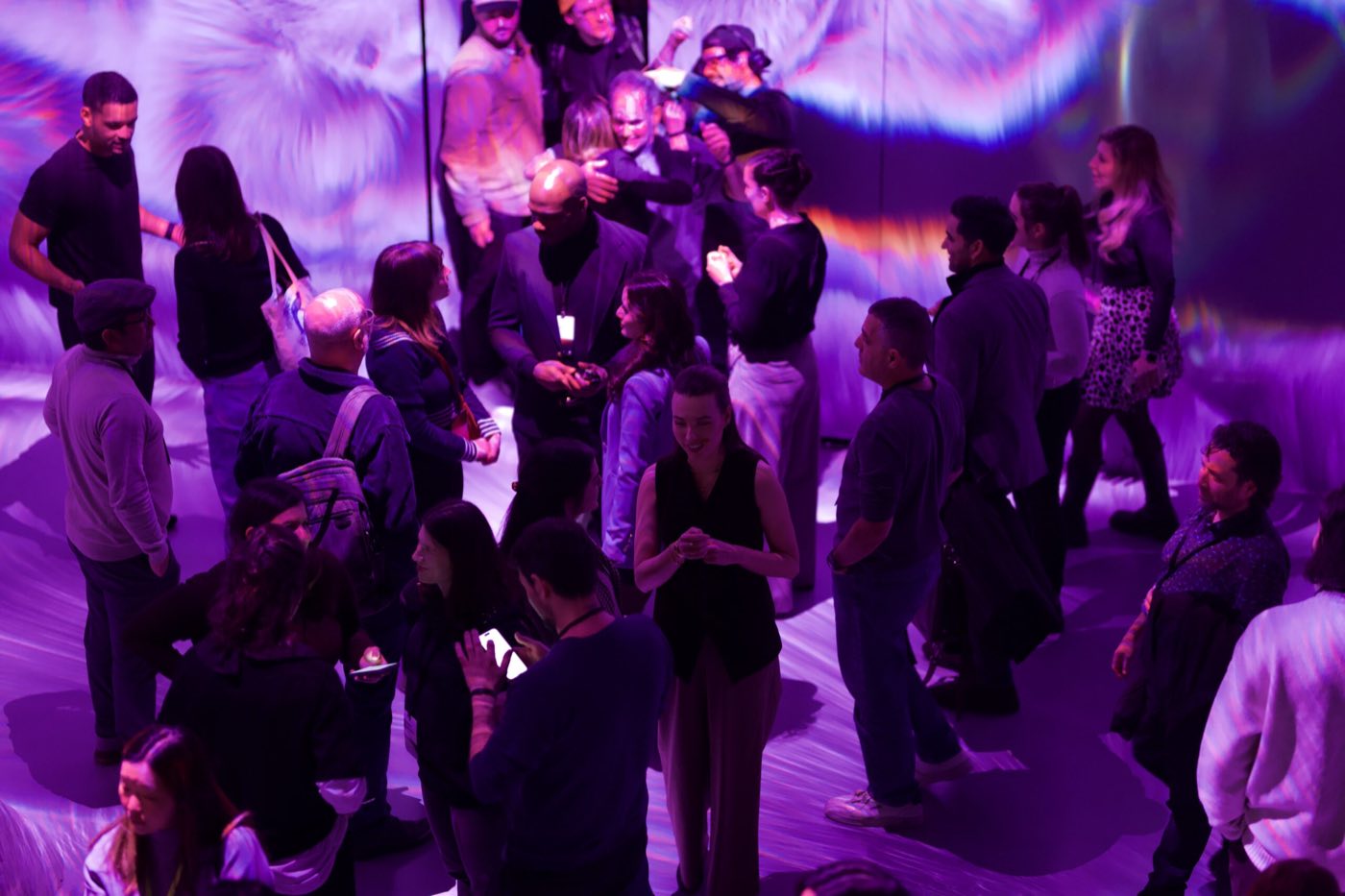Reception crowd seen from above in a room washed with purple wall and floor projection