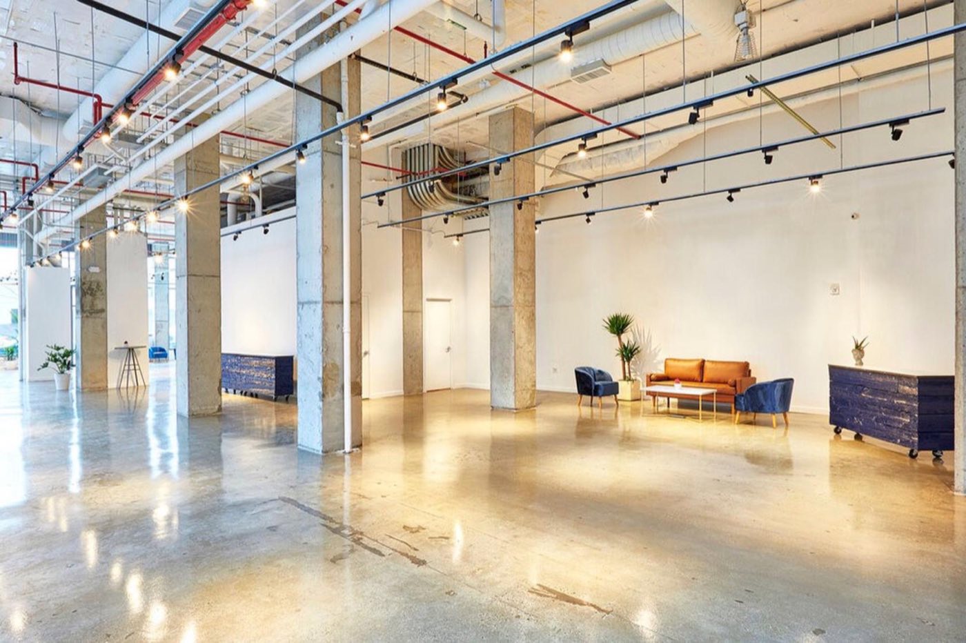 Empty ground floor event space with concrete floors, columns and track lighting