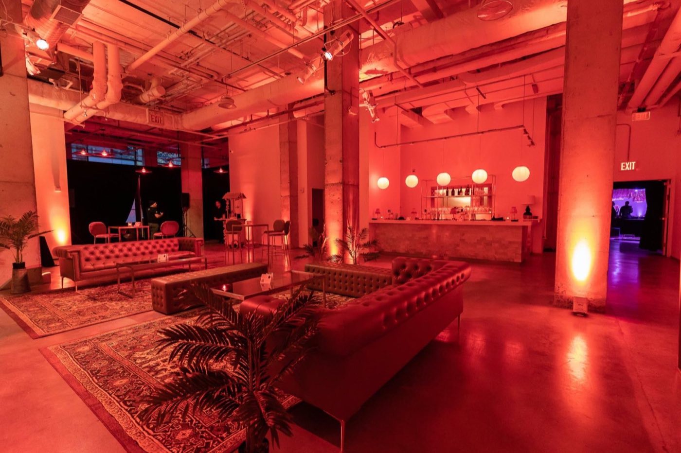 Lounge set with sofas, rugs and bar under red uplighting
