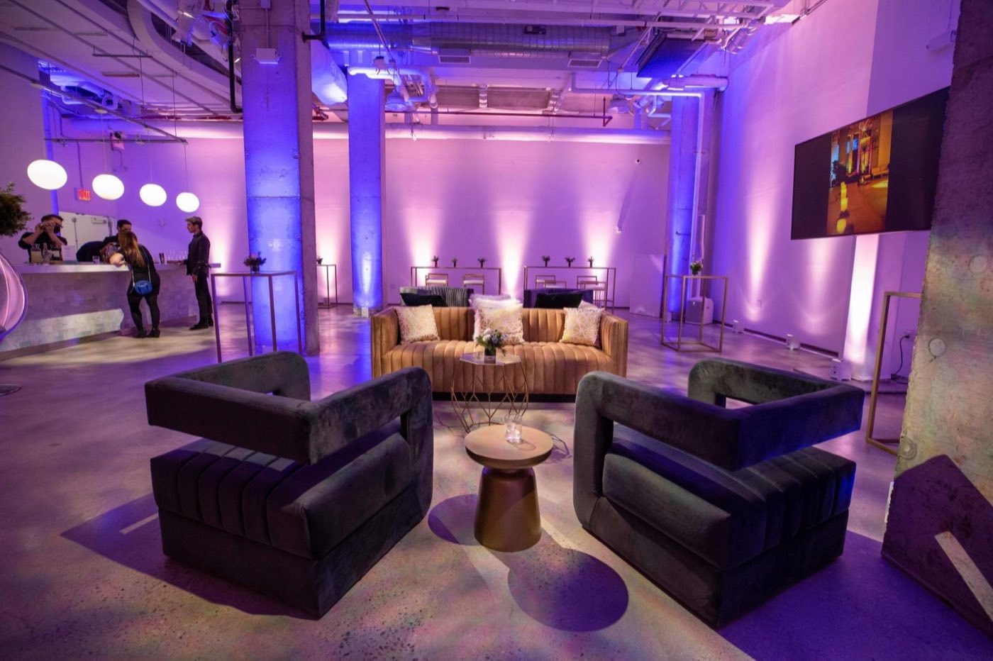 Lounge seating area with velvet chairs and purple uplit columns