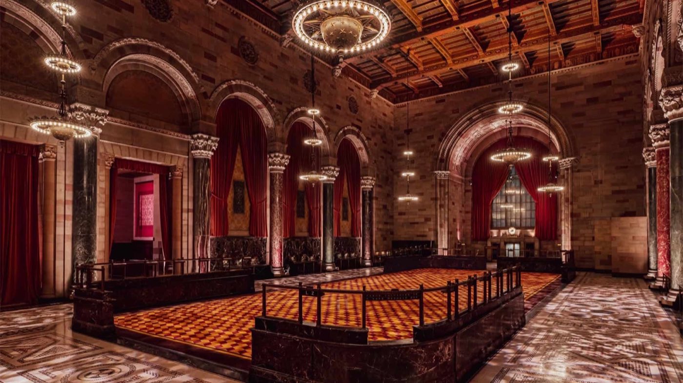 Empty main hall with marble columns, arched windows and a checkered carpet floor