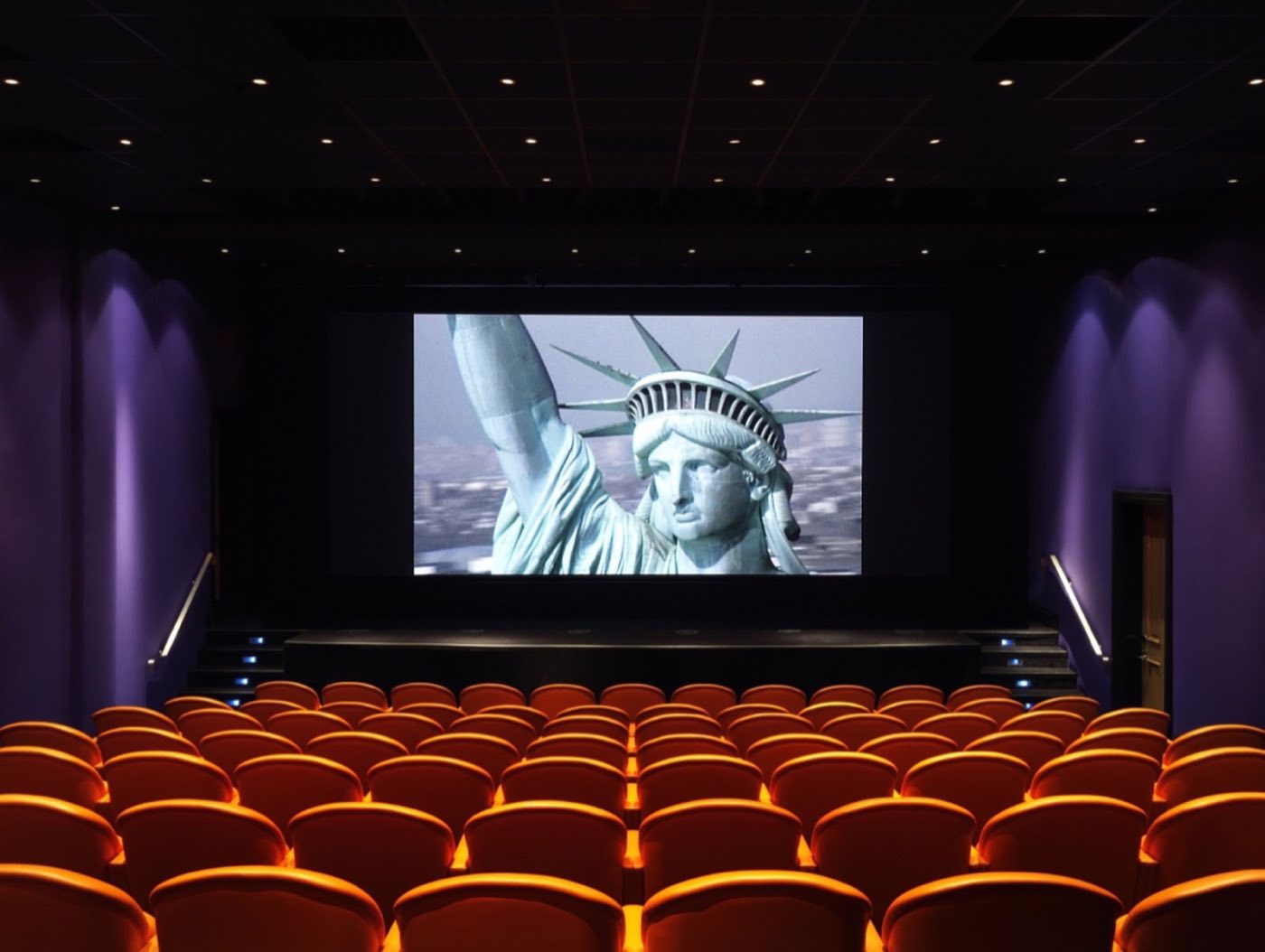 Private screening room with rows of red seats facing a large cinema screen
