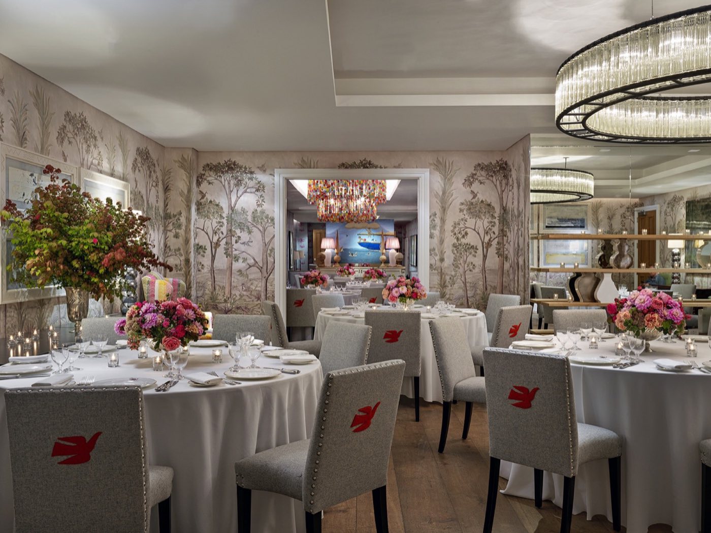 Prince room set with round dinner tables under chandeliers and painted wallpaper