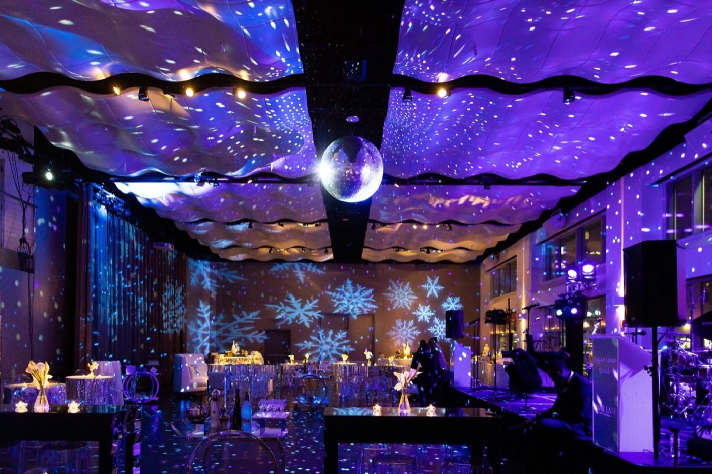 Room lit purple with snowflake projections and a disco ball over the dance floor