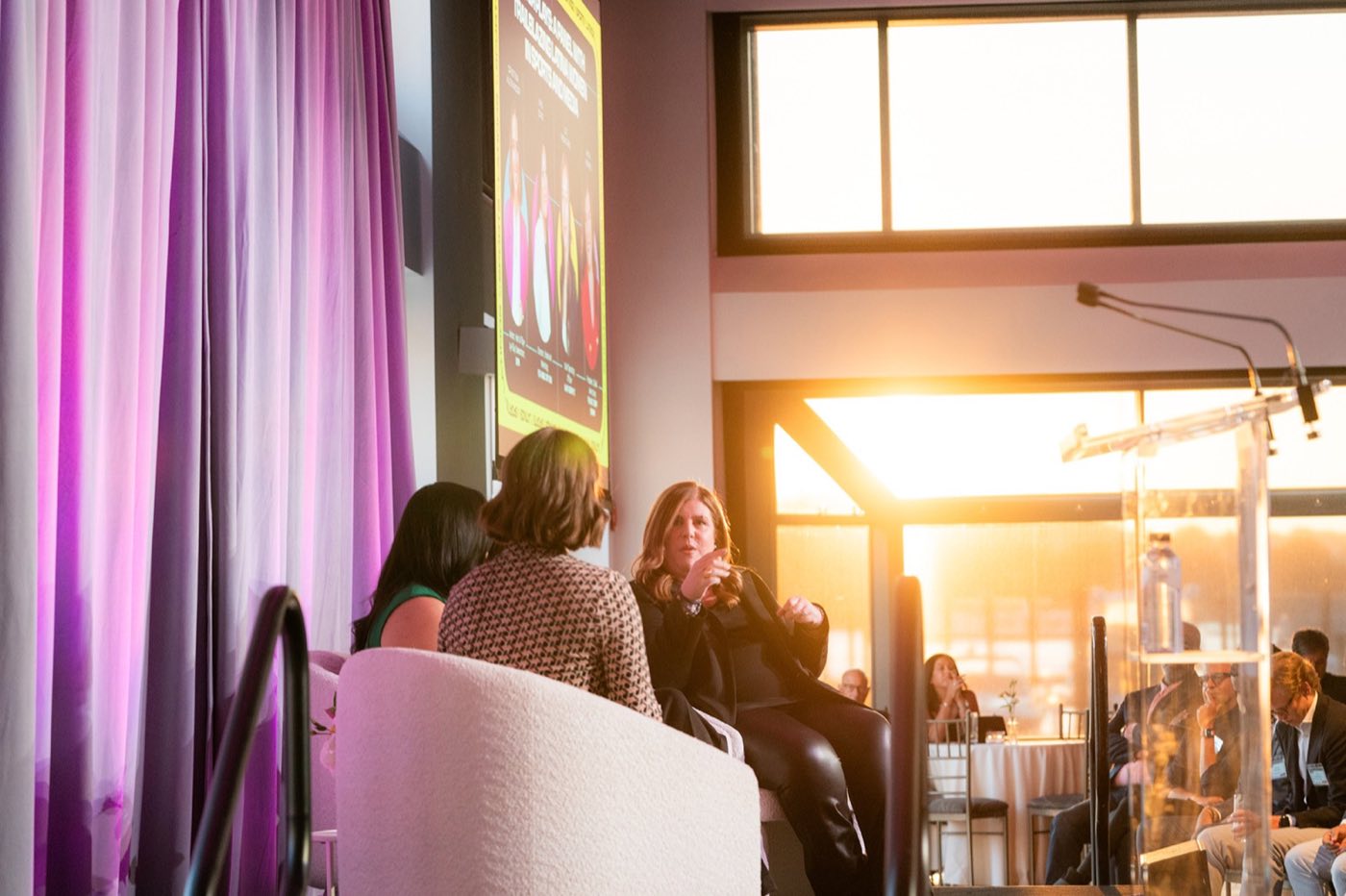 Panel discussion on a stage by the windows at sunset over the Hudson