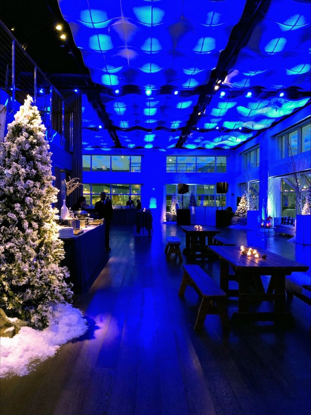 Room lit blue with long tables, lounge seating and a winter decor installation