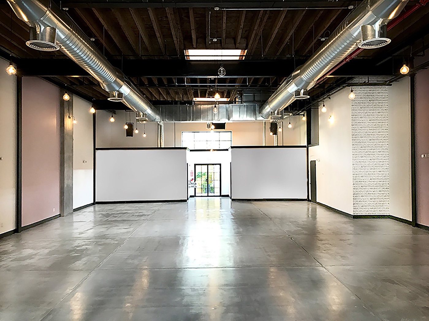 Empty main space with polished concrete floor, skylights and a glass entrance